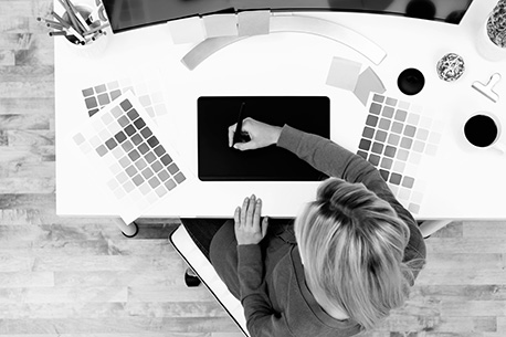 overhead shot of lady working at desk sketching with color pallettes dispersed around her